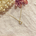 Collar Círculo Corazón sobre arena con flor rosa