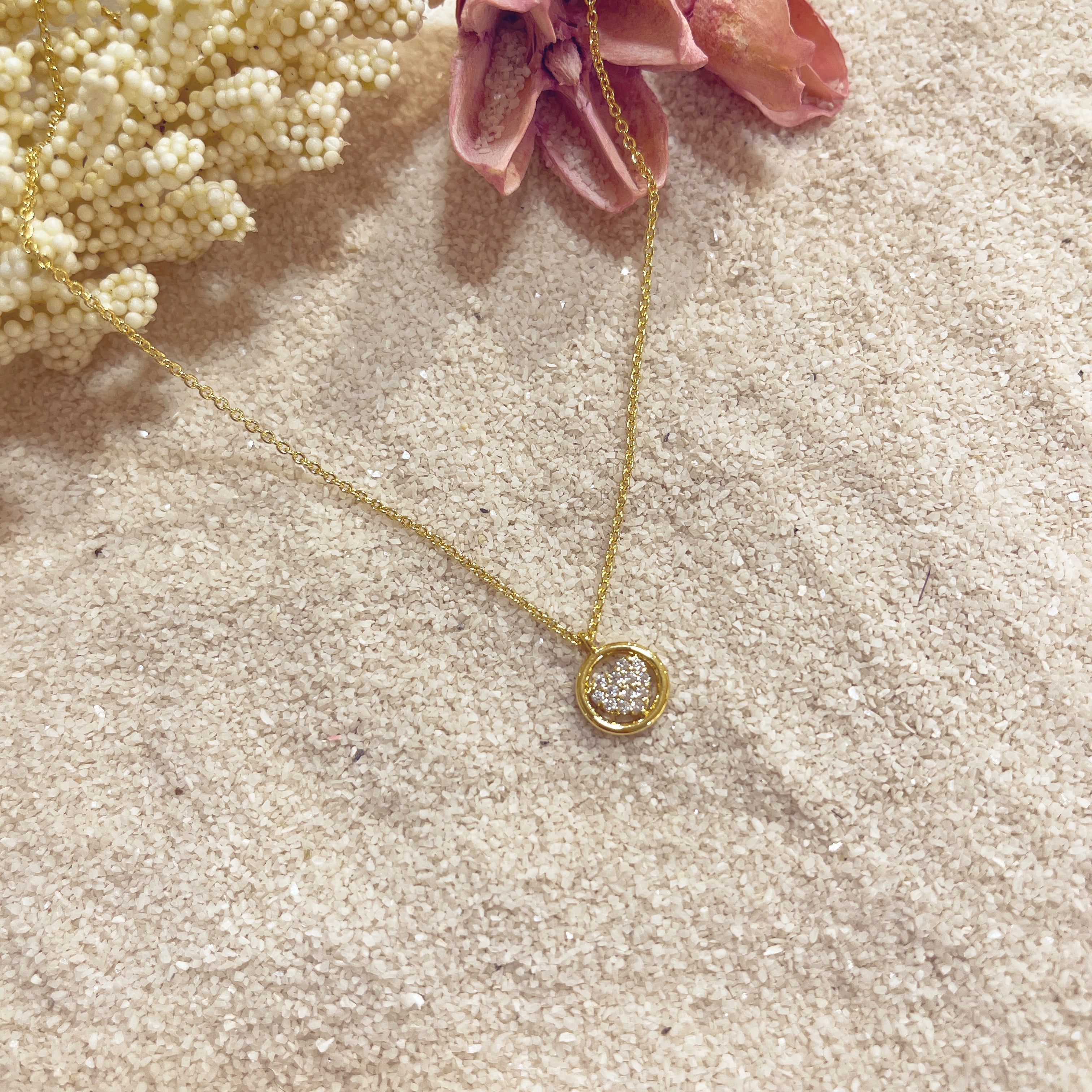 Collar Círculo Corazón sobre arena con flor rosa