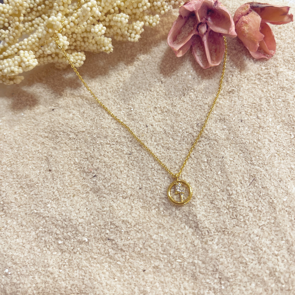 Collar Círculo Rayo sobre arena con flor rosa