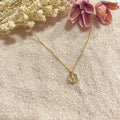 Collar Círculo Rayo sobre arena con flor rosa