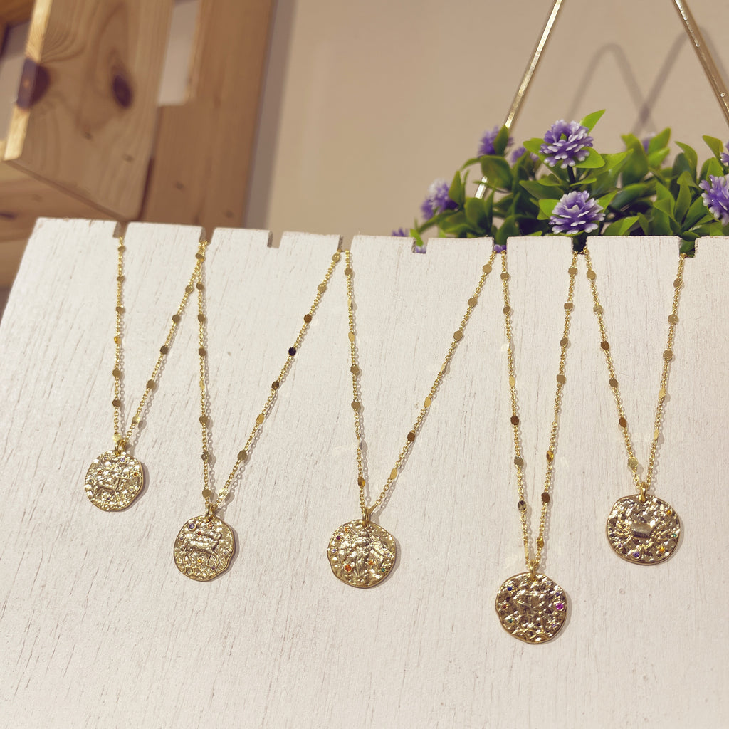 Colección Zodiac cinco medallones dorados en expositor blanco