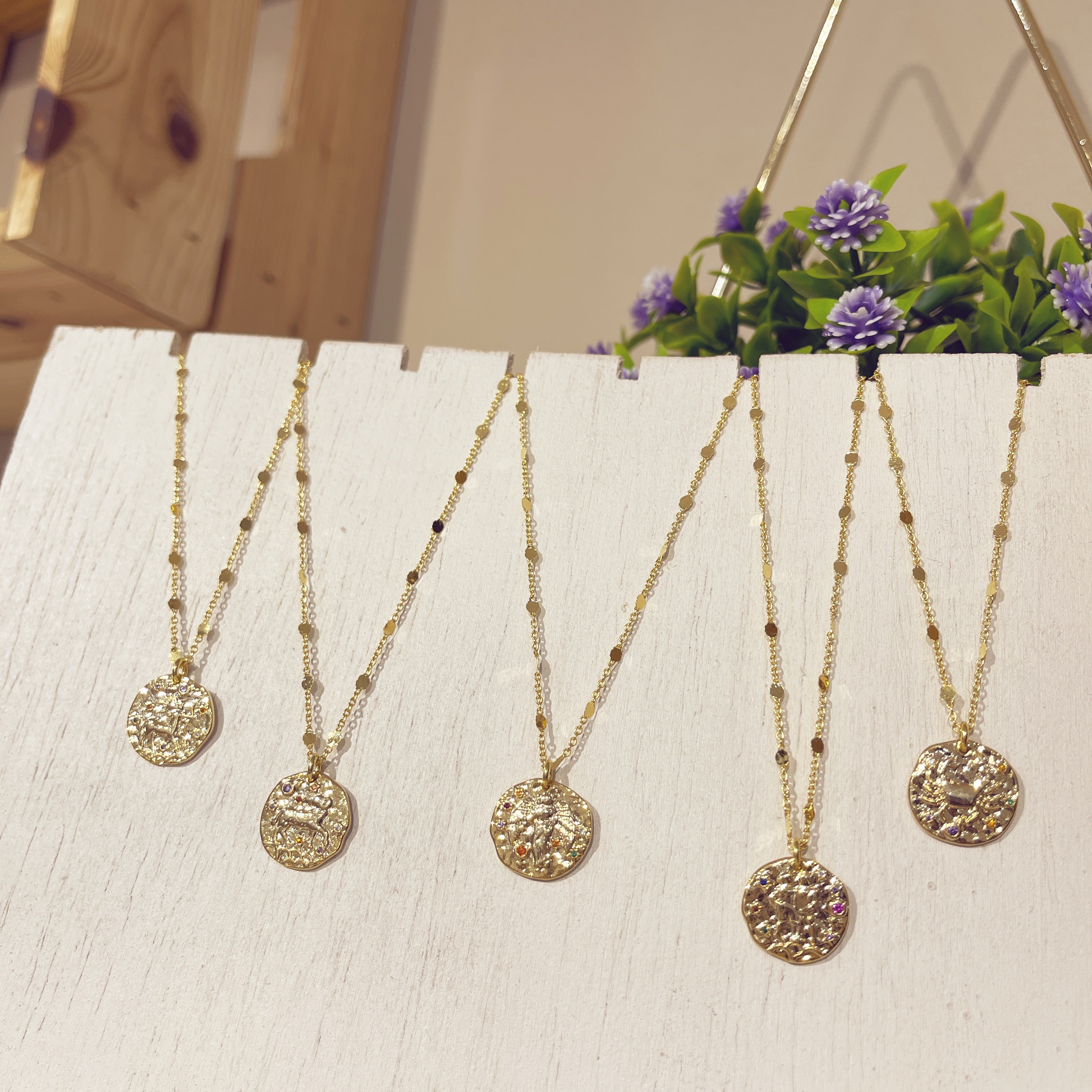 Colección Zodiac cinco medallones dorados en expositor blanco