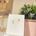 Pendientes minis hoja dorada sobre expositor blanco