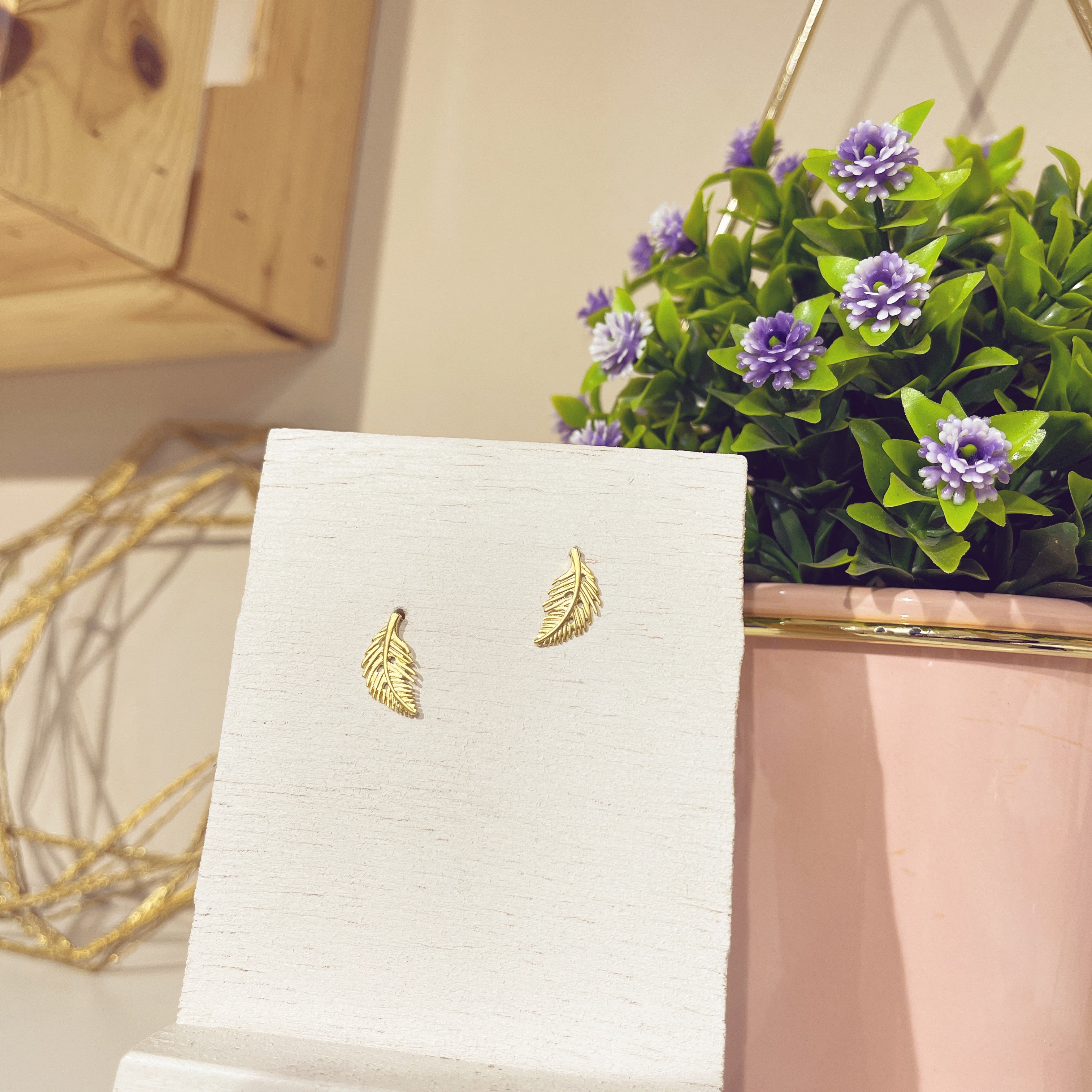 Pendientes minis hoja dorada sobre expositor blanco