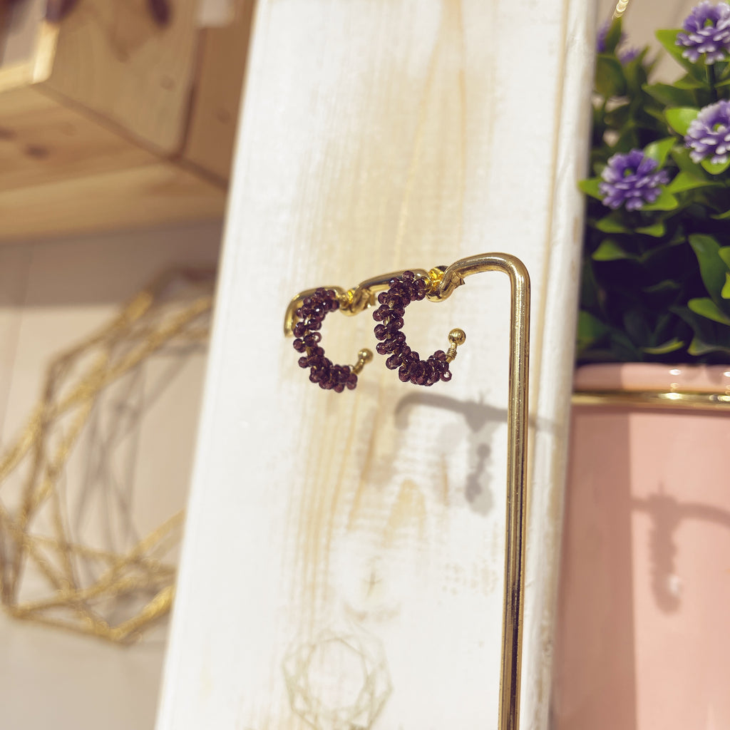 Aro enredado café dorado colgado en expositor dorado, vista lateral