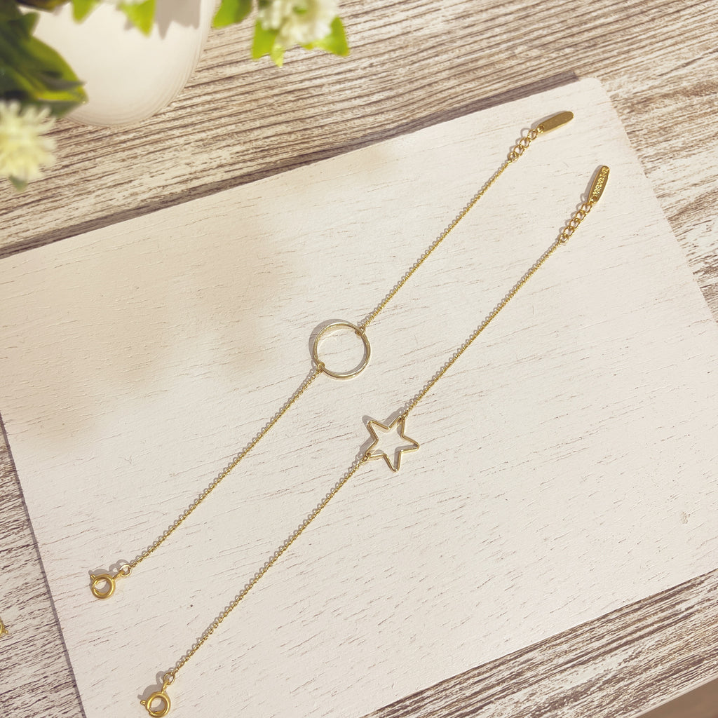 Pulseras Stella doradas círculo y estrella sobre superficie blanca