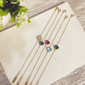 Pulseras Piedra Doblada doradas con piedras de colores sobre superficie blanca