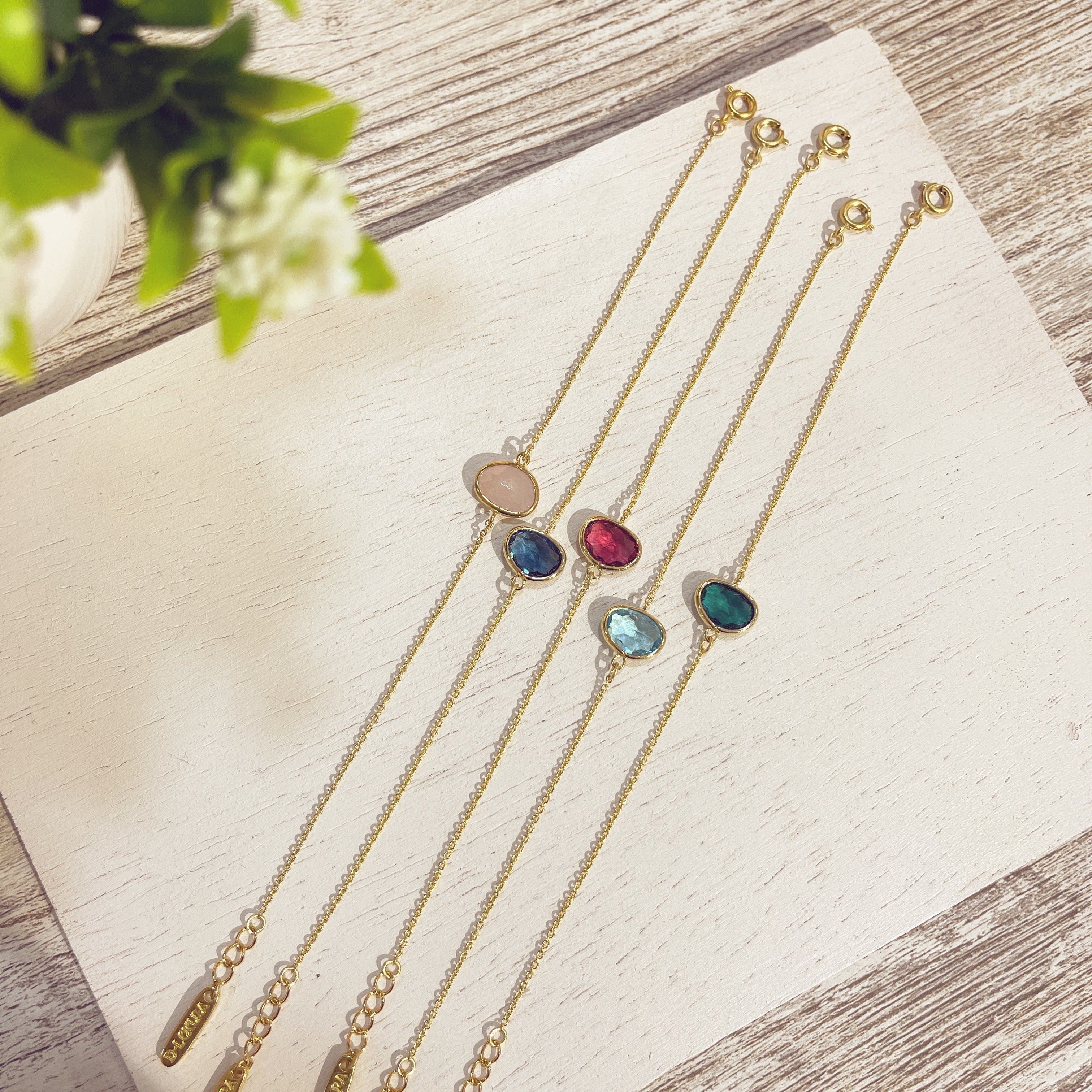 Pulseras Piedra Doblada doradas con piedras de colores sobre superficie blanca