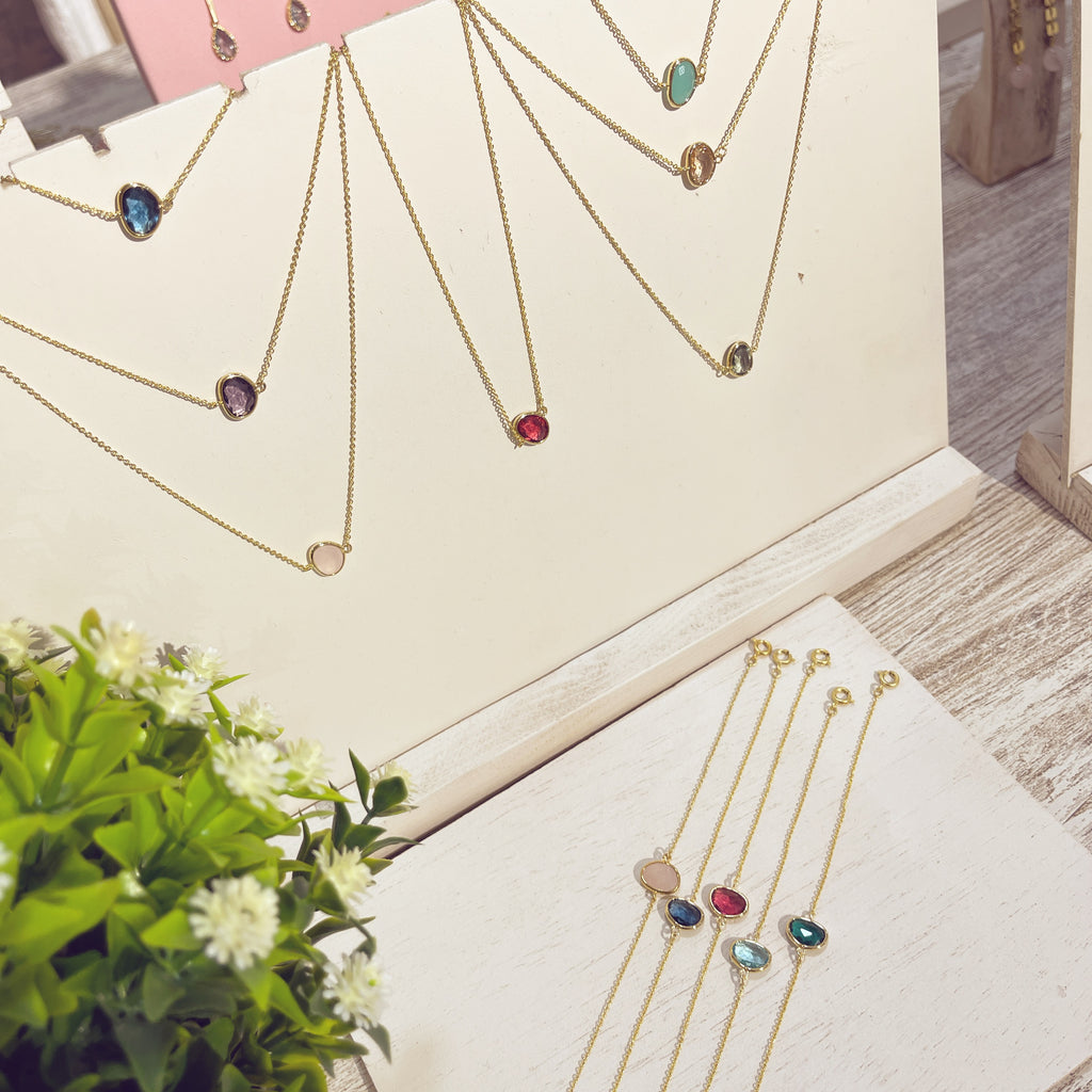 Colección pulseras y collares Piedra Doblada dorados con piedras de colores en expositor
