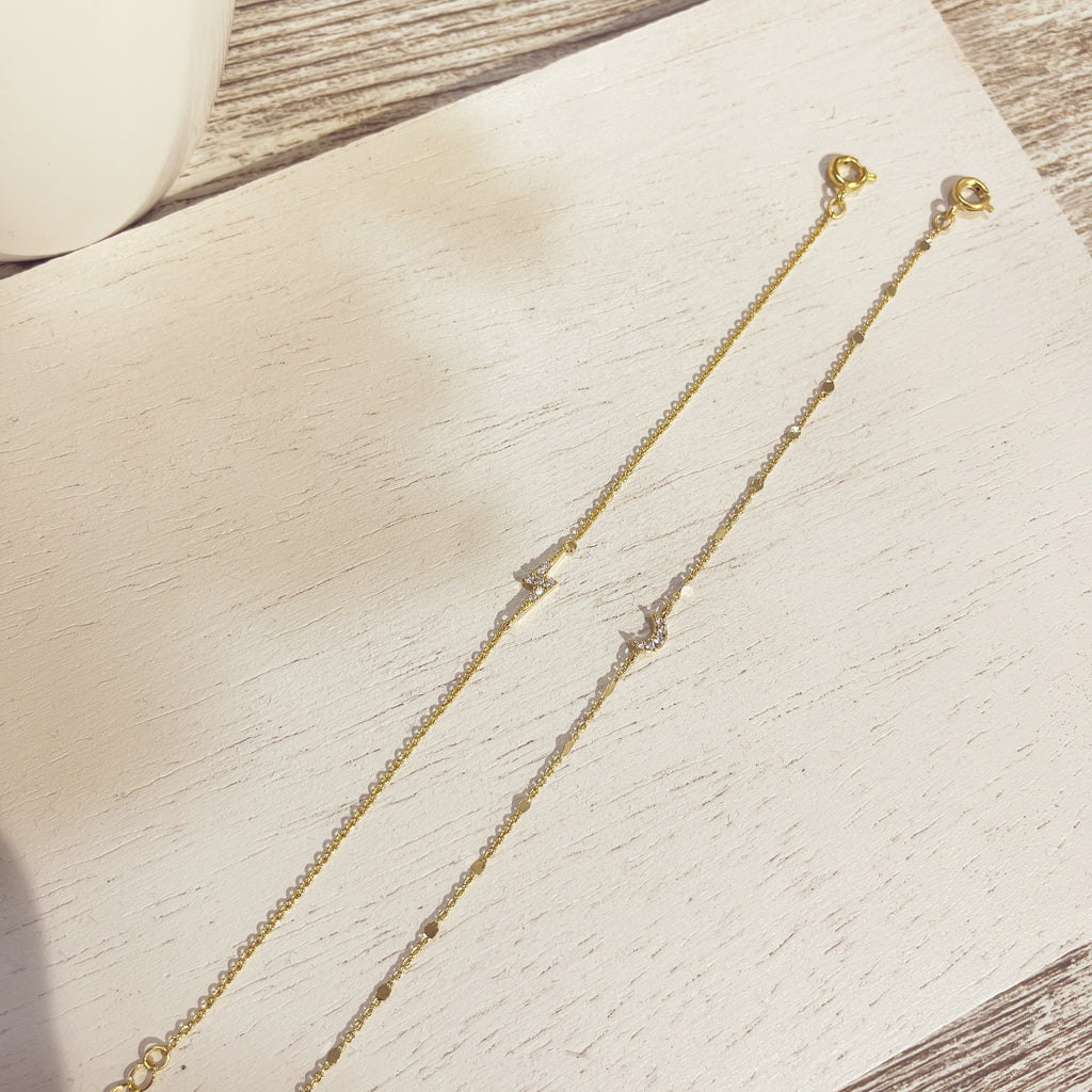 Pulseras Luna Circón doradas sobre superficie blanca