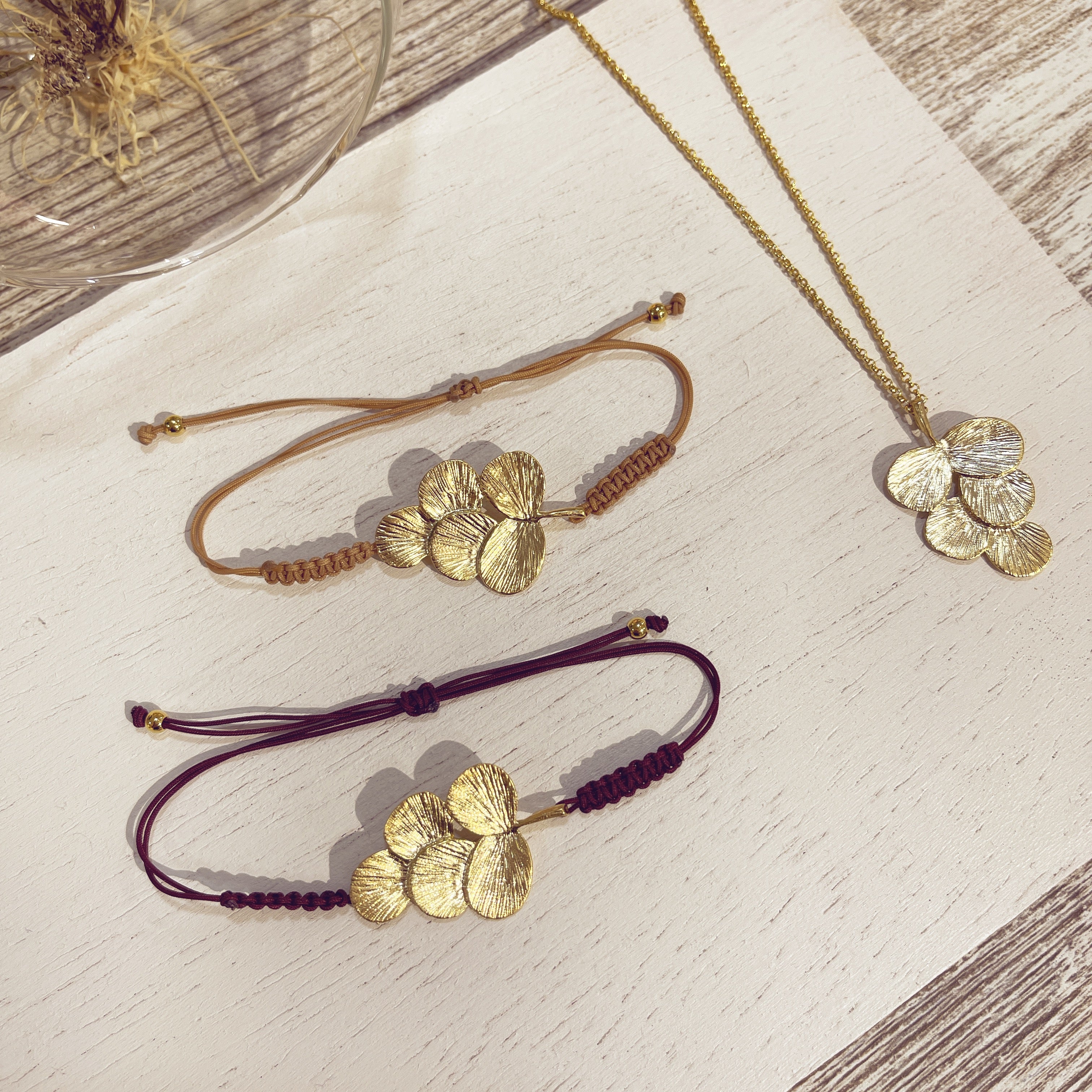 Pulsera Racimo y collar dorados sobre superficie blanca
