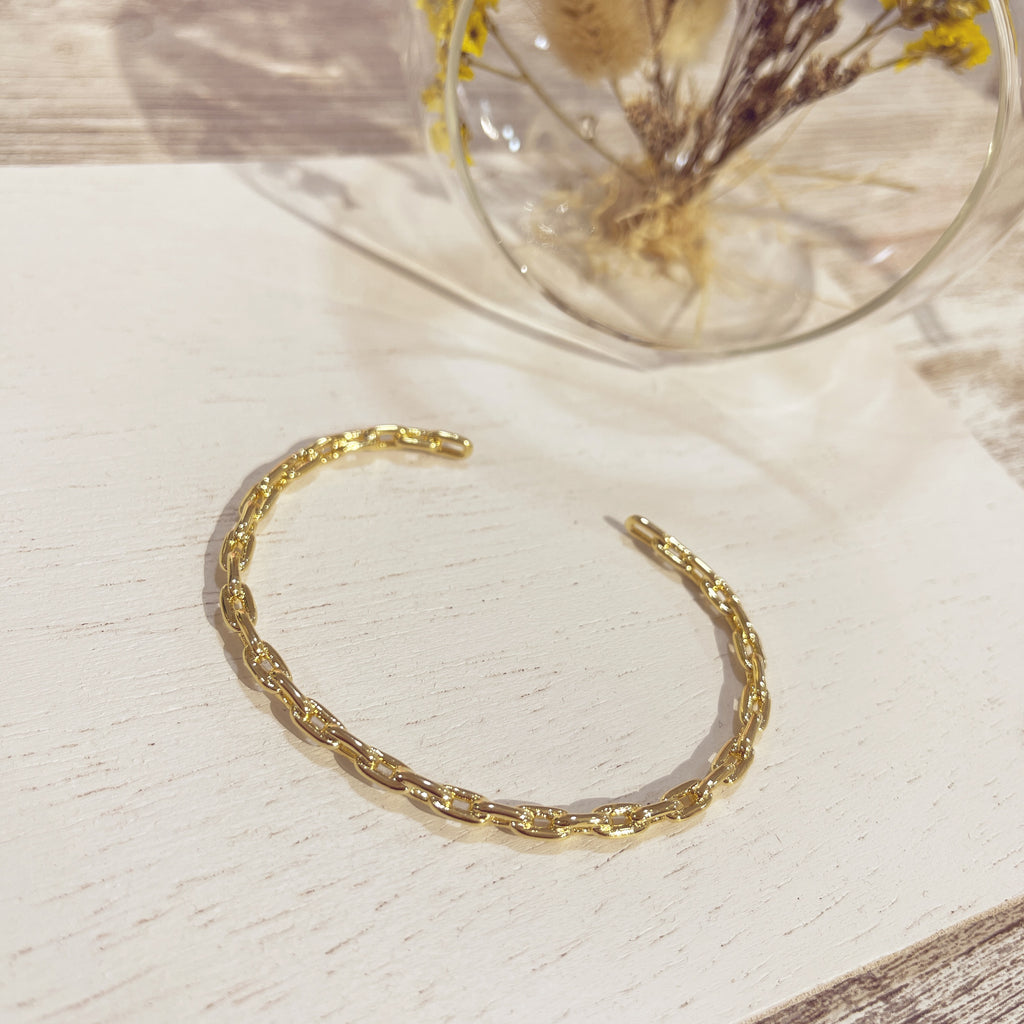 Brazalete Eslabón dorado texturizado sobre superficie blanca