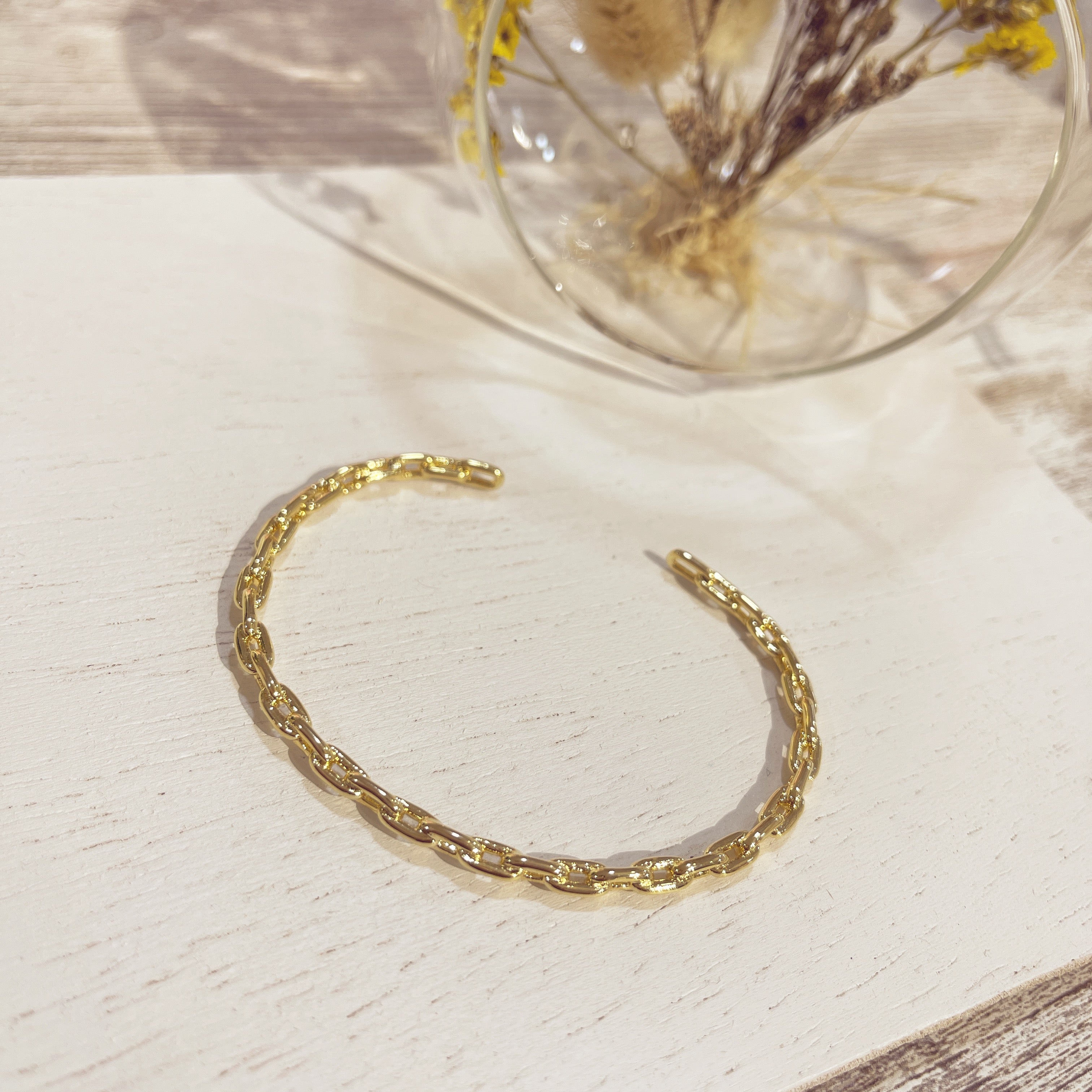 Brazalete Eslabón dorado texturizado sobre superficie blanca
